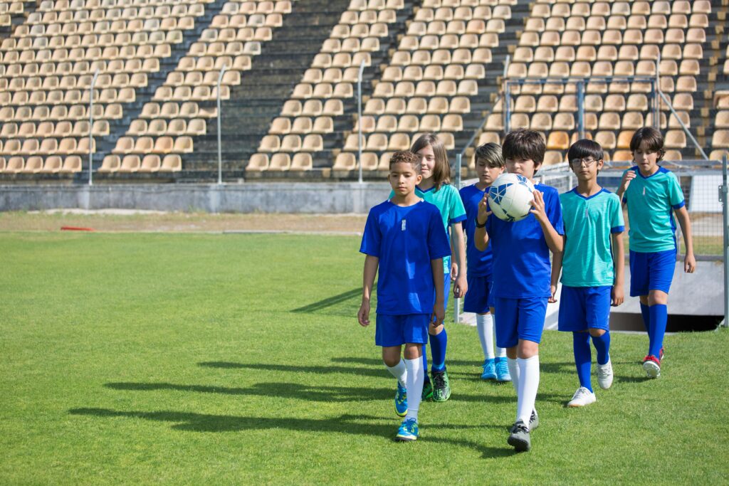 Kids playing soccer on a sunny day, showcasing teamwork and leadership.